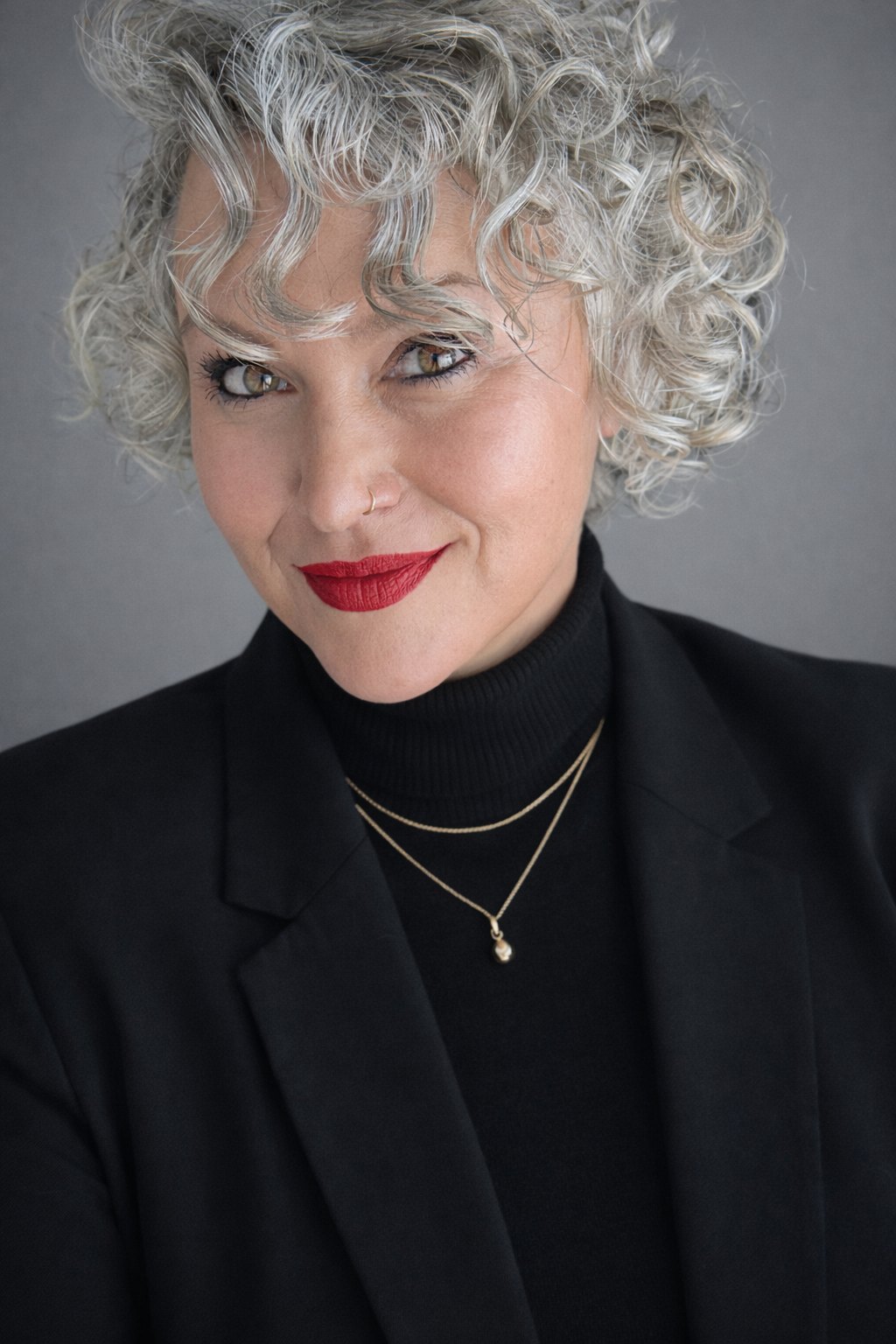Nicole North, keynote speaker, in a black blazer against a grey backdrop